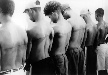 Santiago Sierra, "Line of 250cm Tattooed on Six Paid People," 1999. Black and white photograph.