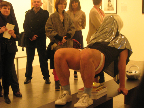 Gutierrez performing an excerpt from, "Retrospective Exhibitionist" squatting over an electric candle. Yours truly on the far left looking like a cynical critic.