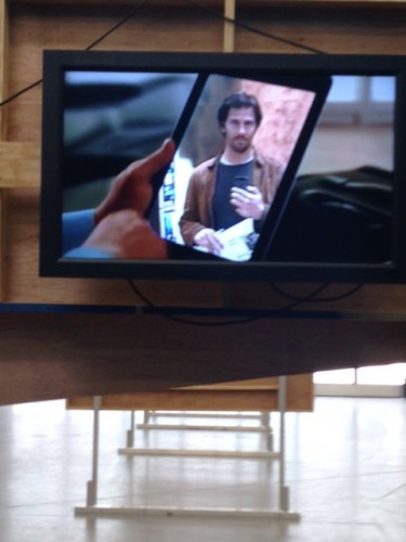 The author taking a picture of his own image as it appears on an iPad screen within a "commercial" running on a flatscreen monitor in Jon Kessler's "The Web." Photo: Max Weintraub