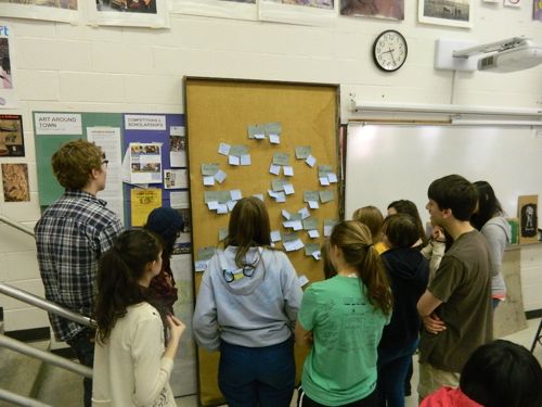 Students in Jack Watson's Studio Art class at Chapel Hill High School contemplate the post-it wall, where they have brainstormed information about areas of conflict for a unit on Borders and Boundaries.  They will later find collaborators using this same wall.