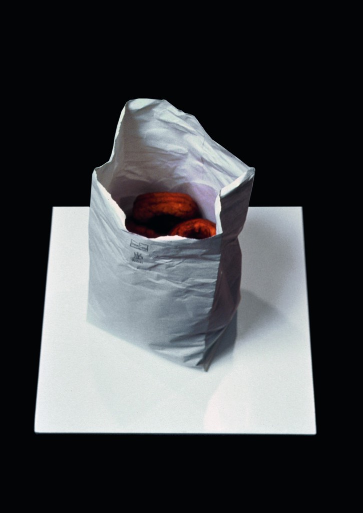 Robert Gober, Bag of Donuts, 1989; acid free hand cut paper, graphite, dough, synthetic resin; edition of 8 with 1 AP; 11 x 6 1/2 x 6 inches. Photo: Geoffrey Clements, Courtesy the artist and Paula Cooper Gallery