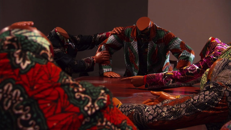Yinka Shonibare MBE, "Scramble for Africa," 2003; 14 life-size fiberglass mannequins, 14 chairs, table, and Dutch wax printed cotton; overall: 52 x 192 1/10 x 110 1/5 inches Installation view, Yinka Shonibare MBE, Museum of Contemporary Art, Sydney, Australia, September 24, 2008–February 1, 2009 Commissioned by the Museum of African Art, Long Island City, New York Collection of The Pinnell Collection, Dallas. Production still from the "Art in the Twenty-First Century" Season 5 episode, "Transformation," 2009. Courtesy James Cohan Gallery, New York and Stephen Friedman Gallery, London © Art21, Inc.