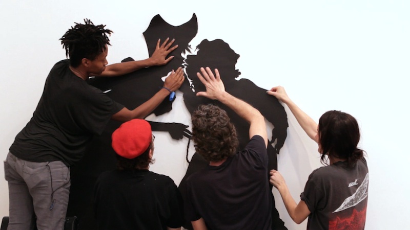 Kara Walker installing "The Nigger Huck Finn Pursues Happiness Beyond the Narrow Constraints of your Overdetermined Thesis on Freedom—Drawn and Quartered by Mister Kara Walkerberry, with Condolences to The Authors" (2010) at Sikkema Jenkins & Co., New York, NY. Production still from the series ART21 "Exclusive." © ART21, Inc. 2014. Cinematographer: Ian Forster.