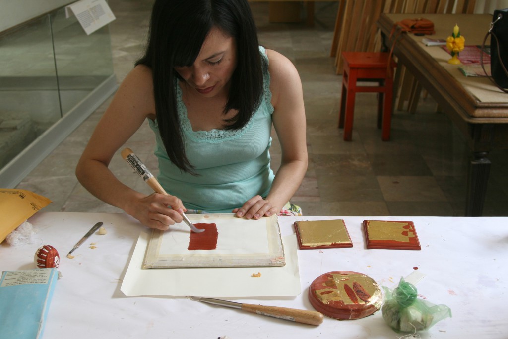 Jocelyn Salaz burnishing the surface of bole on paper in preparation for gold leaf.