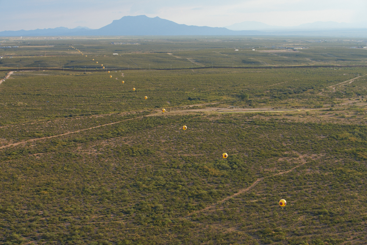 Aerial photograph showing the two-mile-long Repellent Fence / Valla Repelente span the desert near Douglas, Arizona, and Agua Prieta, Sonora. Photo: Michael Lundgren. Courtesy of Postcommodity.