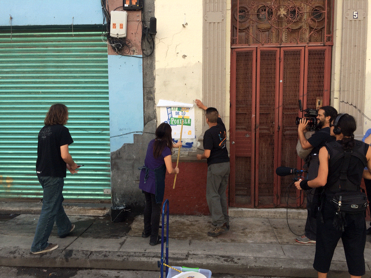 ART21 filming Minerva Cuevas hanging a poster in Tepito, the artist’s neighborhood in Mexico City, Mexico, 2015. The poster reads, “Contra lo prohibido, las calles de lo posible (Against the Forbidden, the Streets of the Possible).” Behind the scenes of ART21’s series Art in the Twenty-First Century, Season 8, 2016. Photo: Ian Forster. © ART21, Inc. 2016.